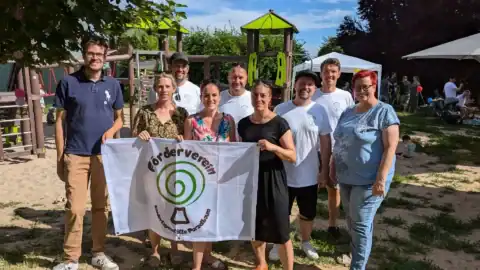 Gruppe mit Banner vor Spielplatz im Freien